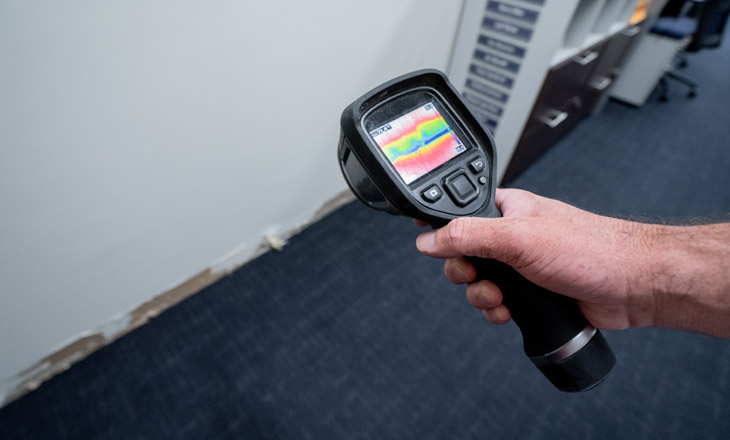 Professional using thermal imaging camera to detect hidden water damage and leaks